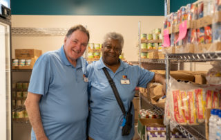 Caucasian male and african american woman posing for a picture in the Food Pantries at Senior Communities