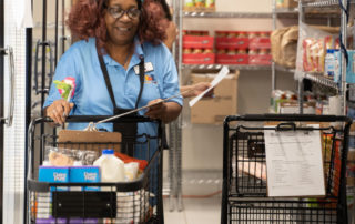 African american woman with brown hair pushing a shopping cart while shopping in the Food Pantries at Senior Communities